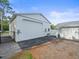 Garage exterior with a large roll-up door, attached generator, and dark asphalt at 15430 Oakcrest Cir, Brooksville, FL 34604