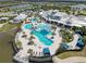 Aerial view of the community pool and patio with ample lounge seating, palm trees, and lake views at 18743 W Coastal Shore Ter, Land O Lakes, FL 34638