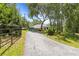 Long driveway leading up to a beautiful blue house surrounded by lush greenery at 22850 Skyview Cir, Brooksville, FL 34602