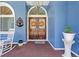 Elegant entryway with double wooden doors, decorative wreaths, and a charming seating area at 22850 Skyview Cir, Brooksville, FL 34602