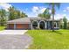 Inviting single-story home with a neatly kept lawn, a mature palm tree, and a three-car garage at 22850 Skyview Cir, Brooksville, FL 34602