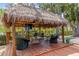 Thatched-roof gazebo on a wooden deck, furnished with comfortable seating and a ceiling fan, perfect for outdoor relaxation at 2295 Rio Cir, Spring Hill, FL 34608
