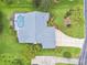 Aerial view showcasing a home with a screened-in pool, lush landscaping, and an expansive driveway at 2519 Shipston Ave, New Port Richey, FL 34655
