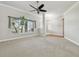 Bright living room features plush carpeting, a large window, and a ceiling fan at 2519 Shipston Ave, New Port Richey, FL 34655