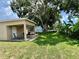 Spacious backyard with a covered patio, a table and chair set, and a large shade tree at 3447 Paloma Dr, Holiday, FL 34690