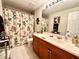 Well-lit bathroom featuring a vanity with wooden cabinets and a shower with a decorative curtain at 3447 Paloma Dr, Holiday, FL 34690
