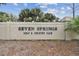 Community sign for Seven Springs Golf & Country Club with lush landscaping and mature trees at 3745 Teeside Dr # 3745, New Port Richey, FL 34655