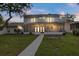 Home exterior with screened patio, balcony, and grassy yard at twilight at 4439 Reeves Rd, New Port Richey, FL 34652