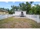 View of charming back house with a white picket fence and a small wooden porch under a cloudy blue sky at 4622 Paloverde Dr, New Port Richey, FL 34652