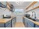 Galley kitchen with butcher block countertops, stainless steel appliances, blue cabinets, and floating wooden shelves at 4622 Paloverde Dr, New Port Richey, FL 34652