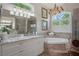 Bathroom showcasing an arched window over a soaking tub, a glass shower and a double vanity at 5072 Abbonmarsh Cir, Brooksville, FL 34604