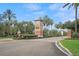 Community entrance with a large stone sign, manicured landscaping and mature palm trees at 5072 Abbonmarsh Cir, Brooksville, FL 34604