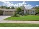 Charming single-story home featuring a lush front lawn, mature landscaping, and welcoming double-door entry at 5072 Abbonmarsh Cir, Brooksville, FL 34604