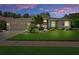Charming single-story home featuring a lush front lawn, mature landscaping, and welcoming double-door entry under a twilight sky at 5072 Abbonmarsh Cir, Brooksville, FL 34604