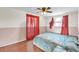 A cozy bedroom featuring wood flooring, a ceiling fan, and colorful curtains that filter natural light at 5543 Moog Rd, New Port Richey, FL 34652