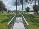 Backyard and pond as seen from the wooden dock, highlighting the green grassy space at 5555 Baffin Cir, Spring Hill, FL 34606
