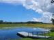 Picturesque view of pond with dock on sunny day with blue skies and fluffy white clouds at 5555 Baffin Cir, Spring Hill, FL 34606