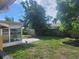 Lush, grassy backyard with a patio area, mature trees, and secure fencing at 7338 Foxbloom Dr, Port Richey, FL 34668