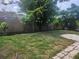 Spacious backyard features a wood fence, mature trees, and a mix of grassy and mulched areas at 7338 Foxbloom Dr, Port Richey, FL 34668