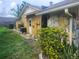 Backyard view featuring a yellow home exterior with partial stone siding and green landscaping at 7338 Foxbloom Dr, Port Richey, FL 34668