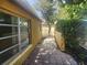 Side exterior with brick patio leading to a lush backyard surrounded by mature trees at 7338 Foxbloom Dr, Port Richey, FL 34668