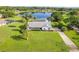 Aerial view of a home with screened pool, lush lawn, and stunning lake views at 8522 Cranes Roost Dr, New Port Richey, FL 34654