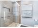 Bathroom featuring a walk-in shower with glass door and tile surround, with a window at 8522 Cranes Roost Dr, New Port Richey, FL 34654