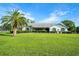 Single-story home boasts arched windows, and a lush green lawn with front-facing palm tree at 8522 Cranes Roost Dr, New Port Richey, FL 34654
