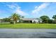 Inviting single-story home with a sprawling green lawn, a prominent palm tree, and manicured shrubbery at 8522 Cranes Roost Dr, New Port Richey, FL 34654