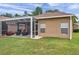 Exterior view of the back of the house showcasing the screened patio, well-manicured lawn, and a fire pit for outdoor enjoyment at 9309 Edistro Pl, New Port Richey, FL 34654