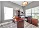 Home office space with a large desk, ergonomic chair, and natural light from two windows at 9309 Edistro Pl, New Port Richey, FL 34654