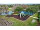 Aerial view of a community playground, tennis court, and pond at 9309 Edistro Pl, New Port Richey, FL 34654