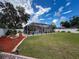 The backyard features a well-maintained lawn, landscaping, and a screened-in pool at 9431 Spring Hill Dr, Spring Hill, FL 34608