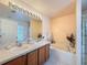 Bright bathroom with double sinks, a large mirror, and a bathtub with shower, perfect for relaxation at 9431 Spring Hill Dr, Spring Hill, FL 34608