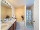 Well-lit bathroom featuring a bathtub, shower, double sinks, ample counter space, and neutral decor at 9431 Spring Hill Dr, Spring Hill, FL 34608