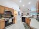 Galley kitchen with stainless steel appliances, wood cabinets, light countertops, tile backsplash and flooring at 9431 Spring Hill Dr, Spring Hill, FL 34608