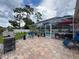 Paver patio boasts grill, seating area and screened pool with privacy fence and landscaping at 9431 Spring Hill Dr, Spring Hill, FL 34608