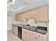 Well-lit kitchen features light wood cabinets, gray countertops, stainless steel dual sink, and tiled flooring at 9433 Stonewall Ln, New Port Richey, FL 34655