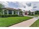 Charming home featuring a well-manicured lawn, lush landscaping, a brick driveway, and a tiled roof at 9704 Milano Dr, Trinity, FL 34655