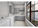 Clean laundry room with grey cabinetry, quartz countertops, modern washer and dryer, and a large window at 9704 Milano Dr, Trinity, FL 34655