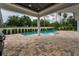 A modern outdoor area with a covered patio, built-in grill, and a luxurious in-ground swimming pool at 9704 Milano Dr, Trinity, FL 34655