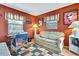 Home office with hardwood floors, orange walls, and a view of the screened pool area through sliding glass doors at 10924 Archway Ave, Hudson, FL 34667