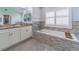 Bright bathroom features a soaking tub with stone surround, double sink vanity, and neutral color palette at 10060 Chip Ln, New Port Richey, FL 34654
