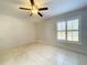 A sunlit bedroom features neutral walls and tile flooring, enhanced by a ceiling fan at 10060 Chip Ln, New Port Richey, FL 34654