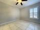Bright, blank bedroom with tile flooring, a ceiling fan and a window with white shutters at 10060 Chip Ln, New Port Richey, FL 34654