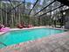 A refreshing screened-in pool is surrounded by brick pavers, with forest views and lounge seating at 10060 Chip Ln, New Port Richey, FL 34654