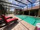 Relaxing screened-in pool with brick pavers and lounge chairs and sunny backyard at 10060 Chip Ln, New Port Richey, FL 34654