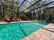 Stunning screened-in pool with forest views, brick pavers, and comfortable lounge seating at 10060 Chip Ln, New Port Richey, FL 34654