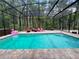 Enclosed pool with brick border, clear blue water, lounge chairs, and lush greenery create a serene backyard oasis at 10060 Chip Ln, New Port Richey, FL 34654