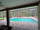 Relaxing screened-in pool with brick pavers, lounge chairs, and a lush wooded view at 10060 Chip Ln, New Port Richey, FL 34654
